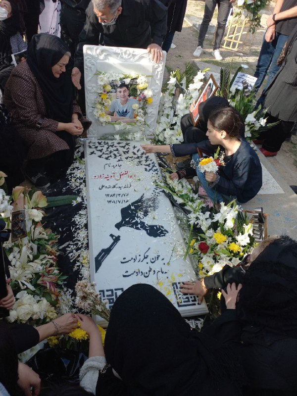 تصویری از سنگ مزار #ابوالفضل_آدینه‌زاده در 'روستای نجف‌آباد #فاروجنوجوان ۱۷ ساله‌ای که روز ۱۶ مهر در مشهد با گلوله‌های ساچمه‌ای نیروهای حکومتی کشته شد.' معلم #ابوالفضل_آدینه‌زاده در مراسم چهلم او که 'زیر جو شدید امنیتی برگزار شد